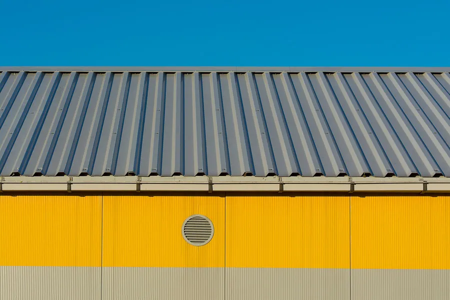 Profiled metal roof and gutter above an industrial building facade